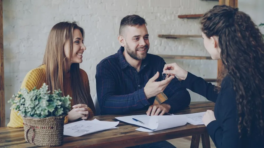 Real estate agent handing property keys to a couple during a meeting